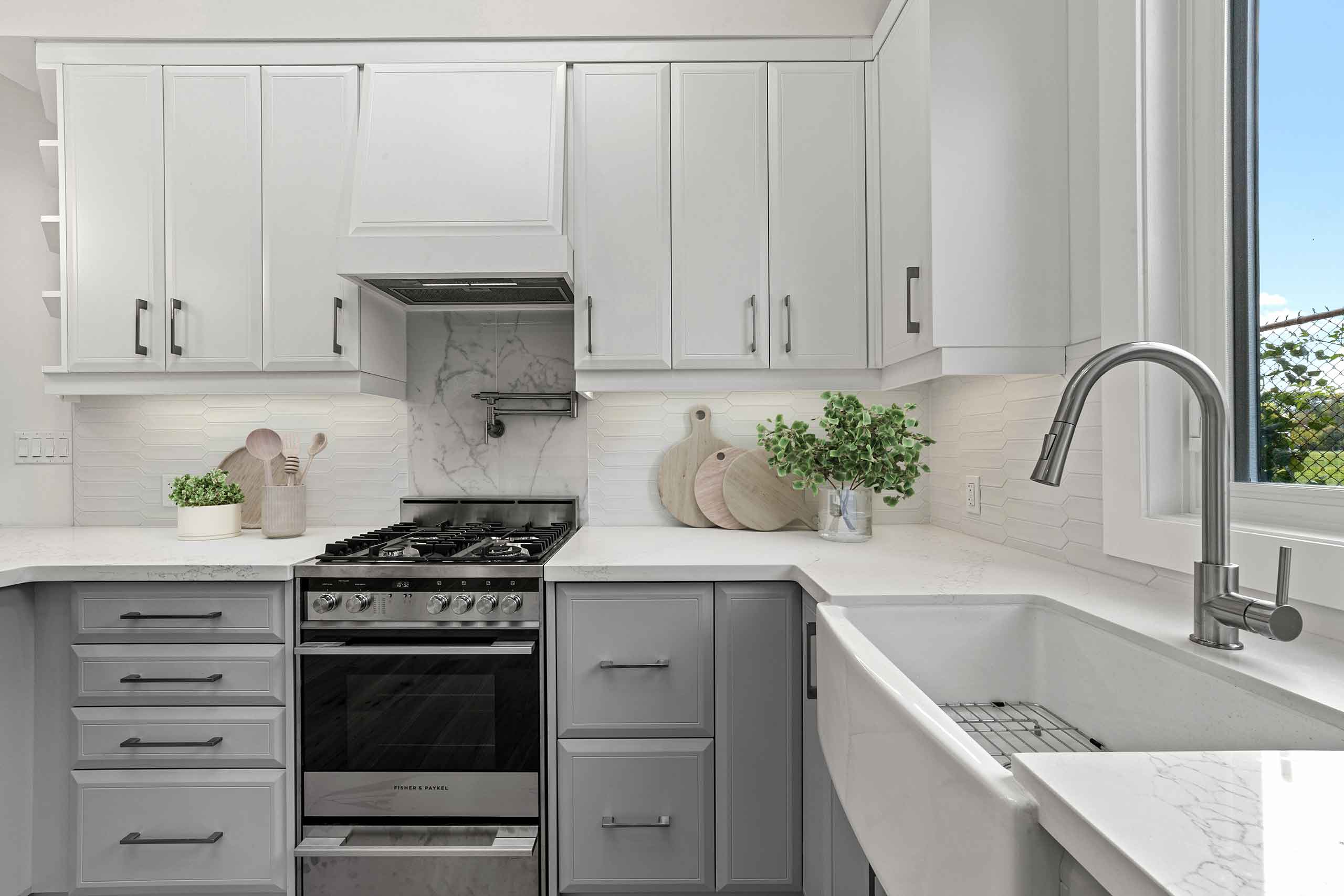 Stylish garden suite kitchen with white and grey cabinetry and farmhouse sink